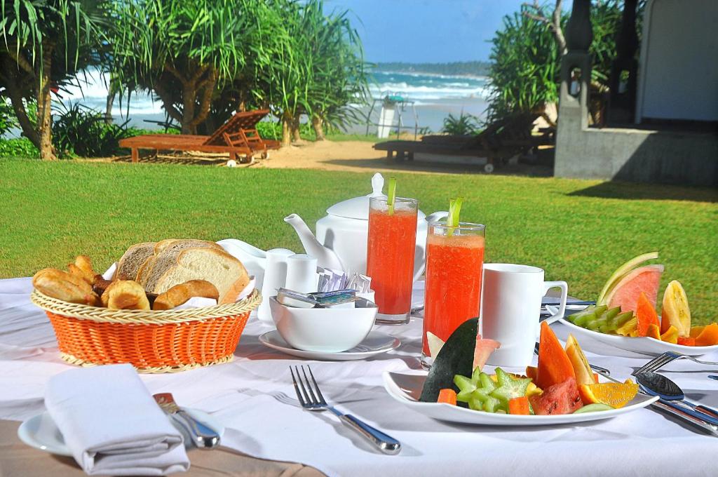 a table with plates of food and a basket of fruit at The Beach Cabanas Retreat & Spa in Koggala