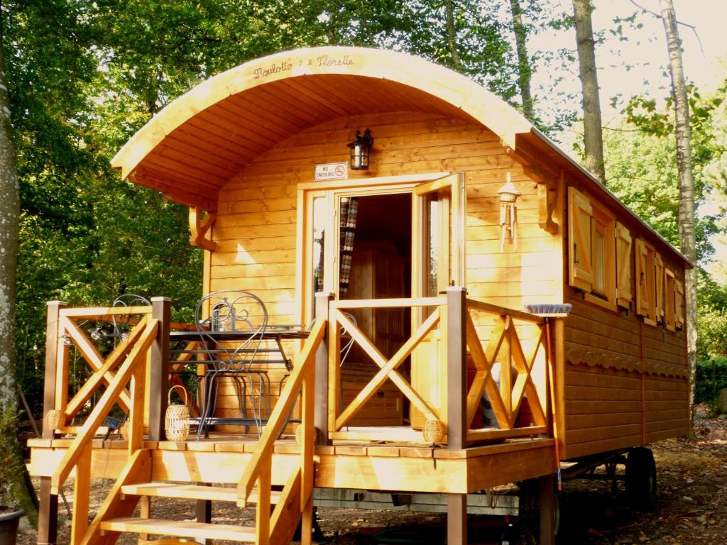 Cette petite cabane en bois dispose d'une terrasse couverte et d'escaliers. dans l'établissement Roulotte Les Deux Geais, à Sainte-Opportune-du-Bosc