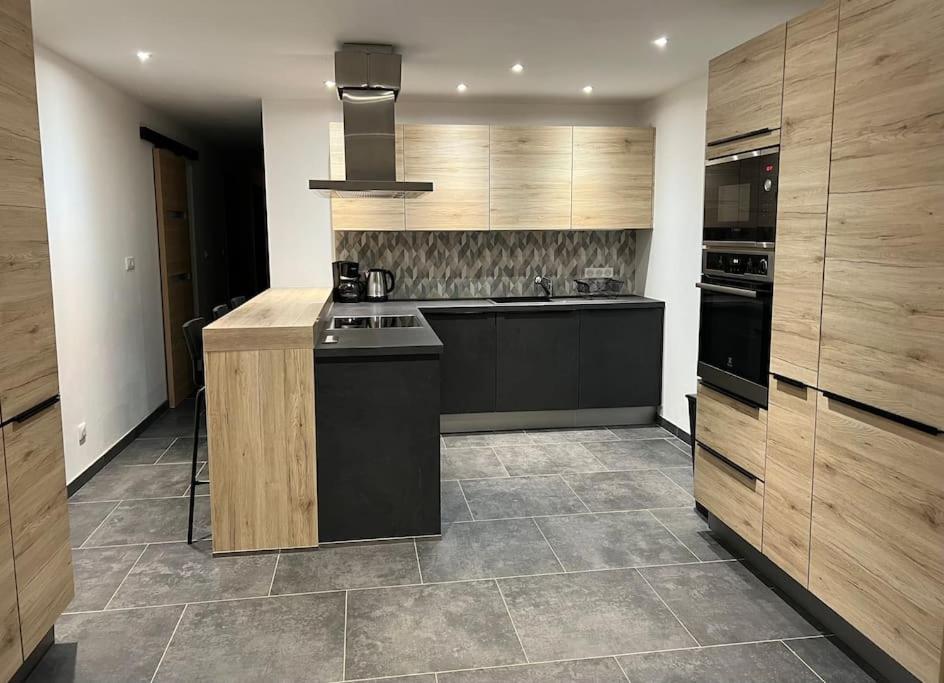 a large kitchen with wooden cabinets and a stove at Sauna et SPA en rez-de-jardin au pied de la montagne in Buhl