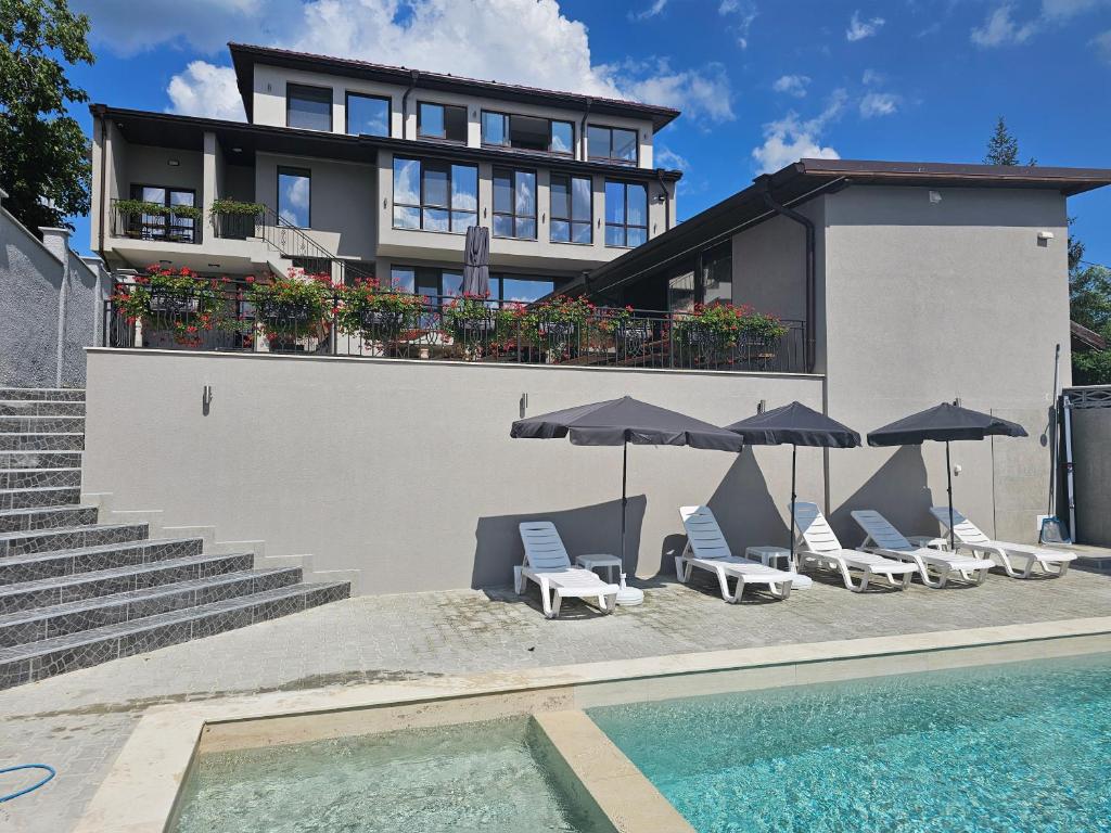 a building with chairs and umbrellas next to a swimming pool at Къща за гости SUNNY HILL in Varna City