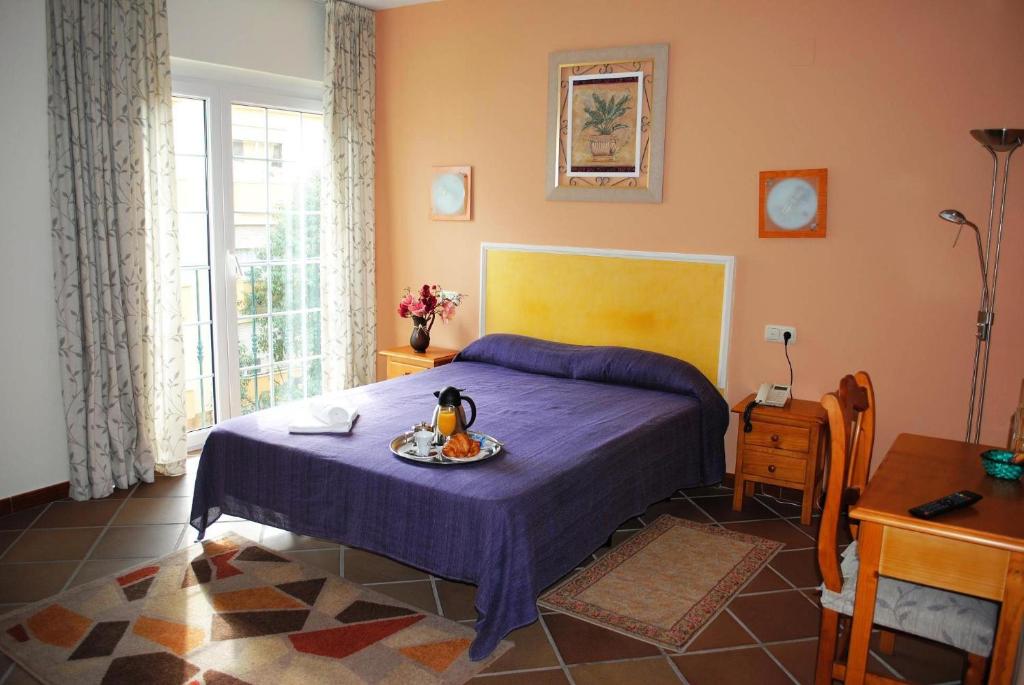 a bedroom with a bed with a plate of food on it at Hotel María Cristina in Cala del Moral