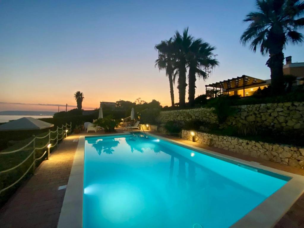 une grande piscine bleue devant un immeuble dans l'établissement Villa Luce, à Syracuse