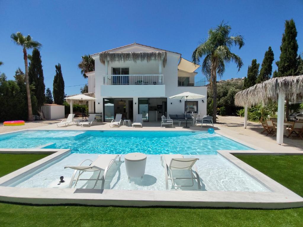 una villa con piscina frente a una casa en Five Palms Villa, en Paphos