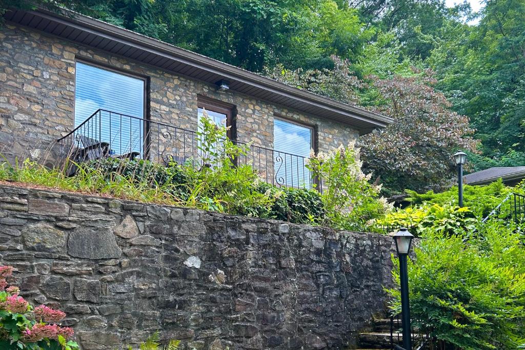 a brick house with a balcony and a stone wall at Stone Cottage 1955 in Lake Junaluska