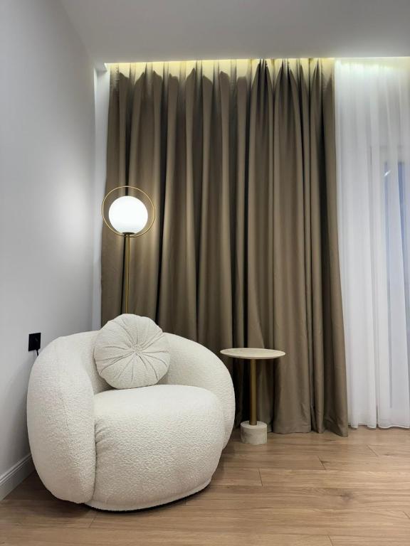 a white chair sitting in a room with a lamp at Hotel Jurgen in Lezhë