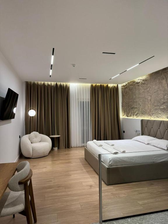a bedroom with a large bed and a chair at Hotel Jurgen in Lezhë