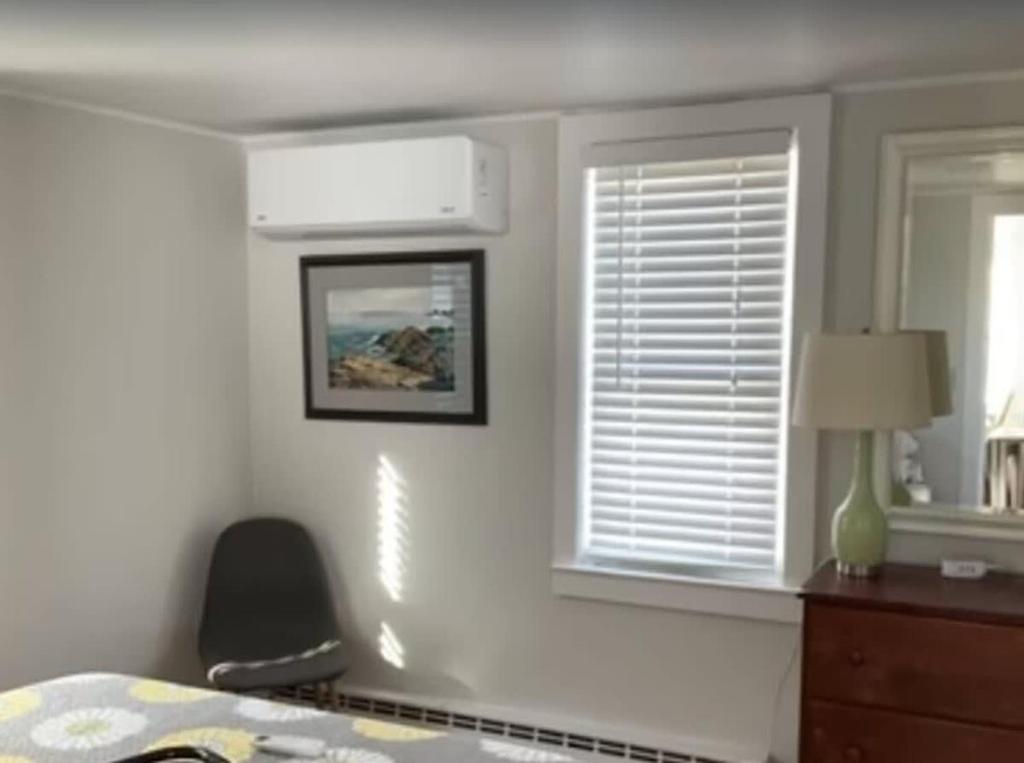 ein Schlafzimmer mit einem Bett, einem Fenster und einem Stuhl in der Unterkunft Charming Cottage with Amazing Views in Truro