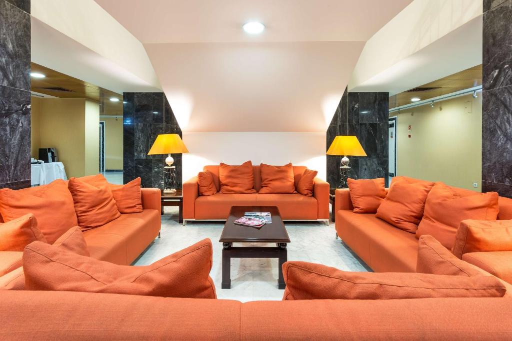 A lounge seating area furnished with orange sofas around a coffee table.
