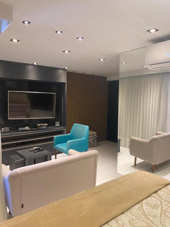 a living room with a tv and a blue chair at Golden Tower - Flat a Beira Mar in Natal