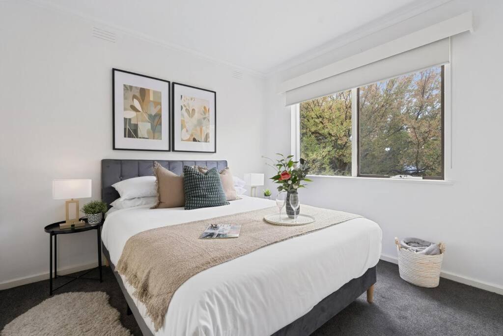 a white bedroom with a large bed and two windows at Urban Oasis Prahran in Melbourne
