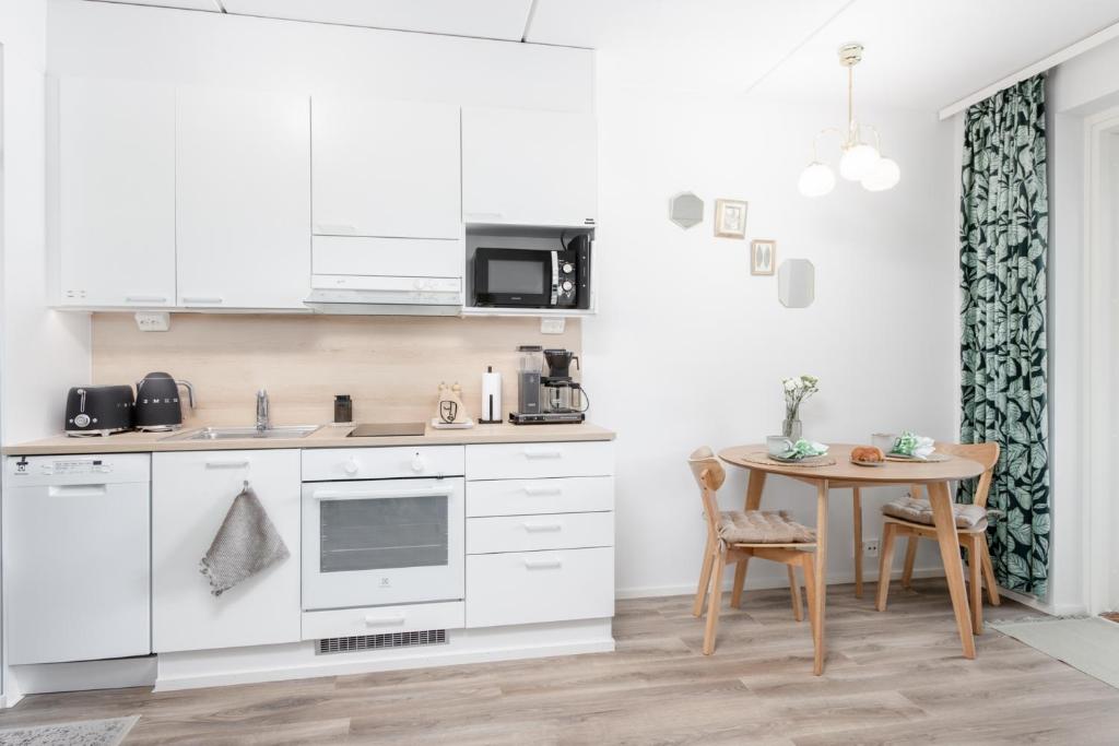 a kitchen with white cabinets and a small table at New studio apartment with free parking in Kuopio