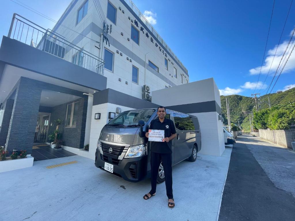 a man is standing in front of a car at HOTEL KANALOA in Tokashiki
