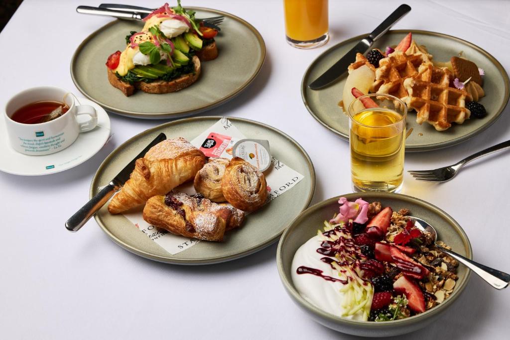 a table with four plates of breakfast foods and drinks at Stamford Plaza Melbourne in Melbourne