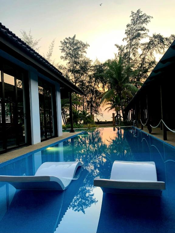 a swimming pool with two lounge chairs in it at Villapadu Bayu in Kuala Terengganu