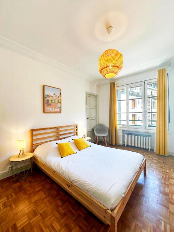 - une chambre avec un grand lit blanc et des oreillers jaunes dans l'établissement Le Chambellan, à Orléans