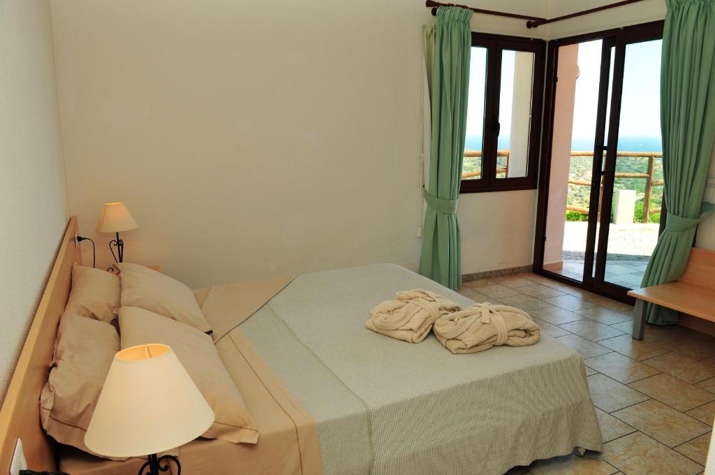 sypialnia z łóżkiem, lampą i oknem w obiekcie Hotel Castello Budoni w mieście Budoni