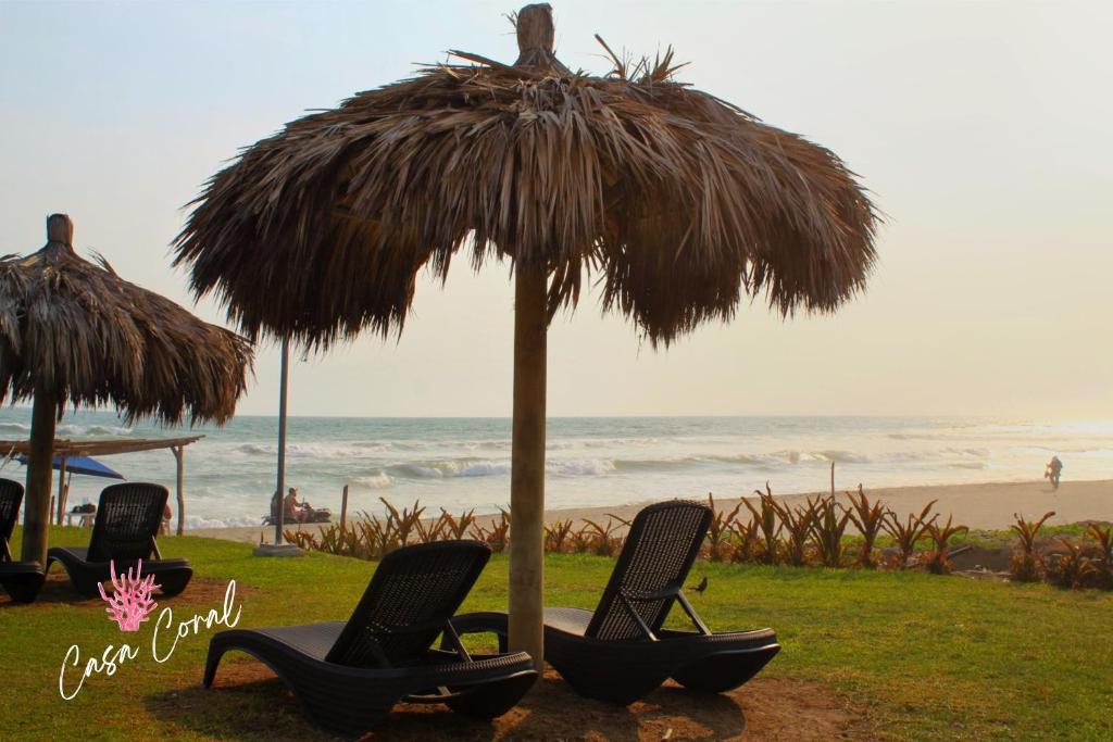 - 2 chaises sous un parasol de paille sur la plage dans l'établissement Depa Coral con Club de Playa Exclusivo Playa Bonfil Diamante, à Acapulco