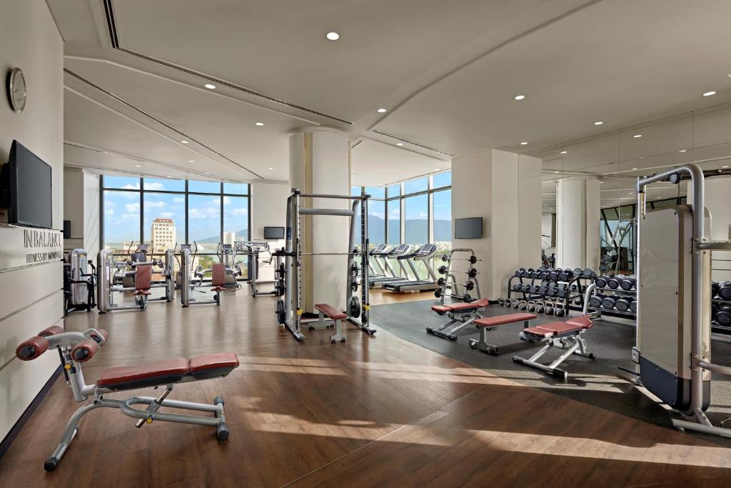 A bright, mirrored gym with cardio machines, strength equipment and free weights.