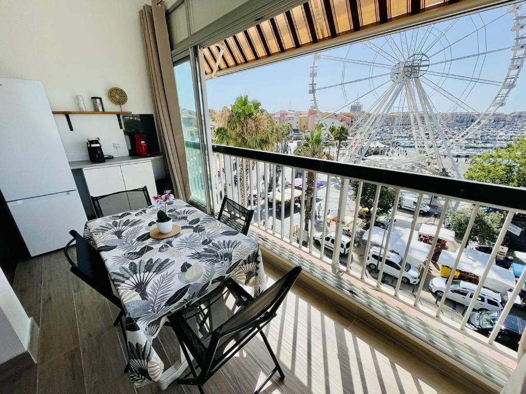d'un balcon avec une table, des chaises et une grande roue. dans l'établissement Bel appartement climatisé en centre-port - FR-1-723-165, au Cap d'Agde