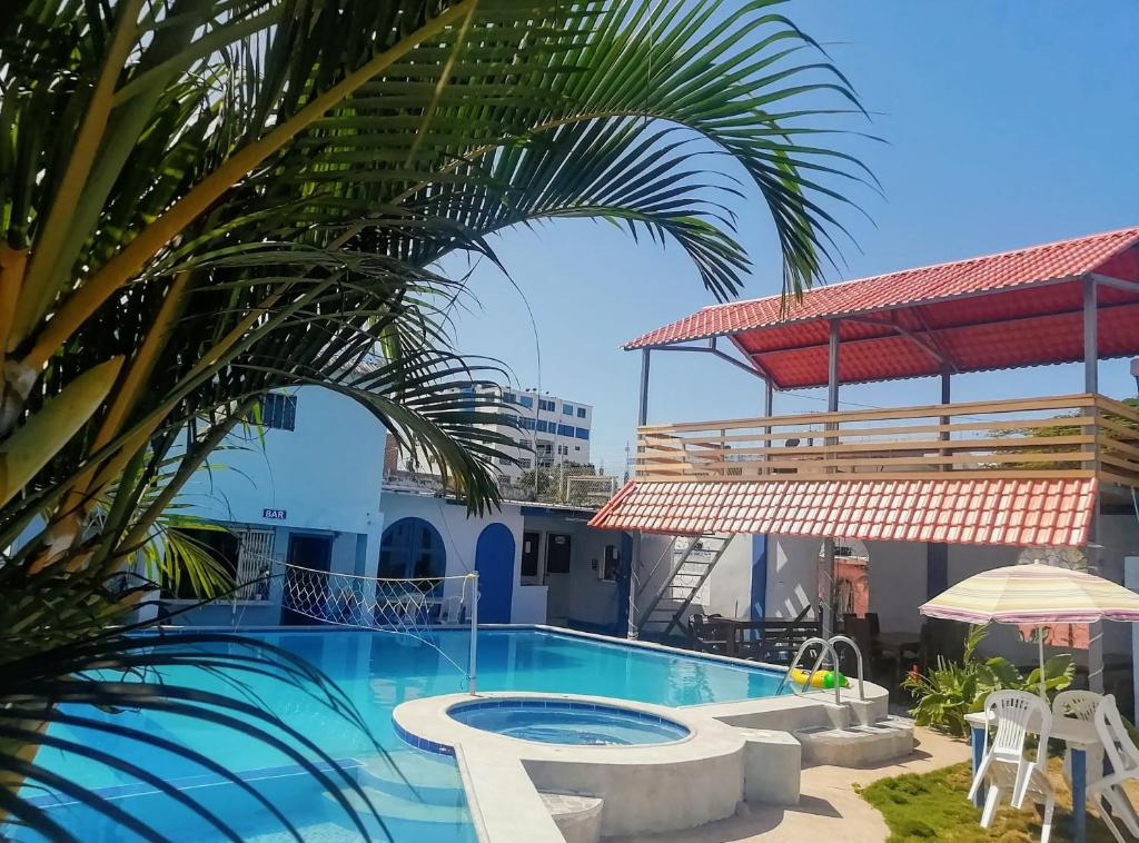 a pool with a palm tree and a building at Hostal Aruba in Atacames
