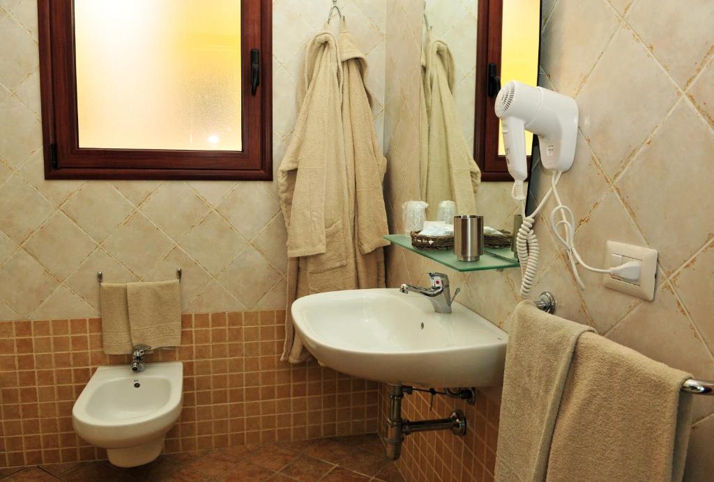 łazienka z umywalką, toaletą i lustrem w obiekcie Hotel Castello Budoni w mieście Budoni