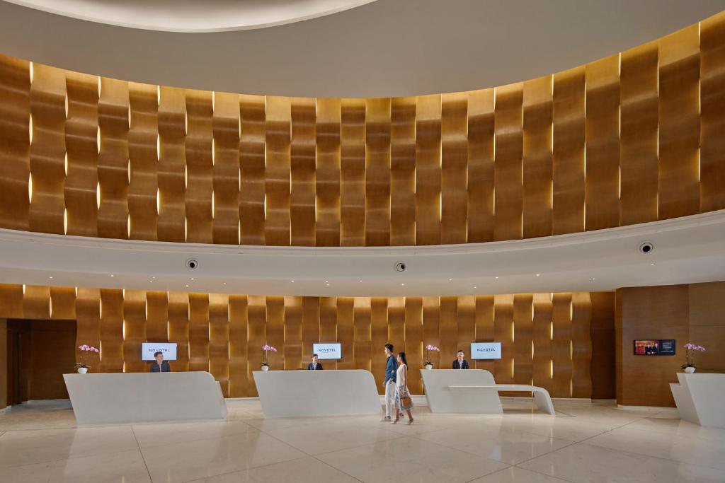 A spacious, polished reception lobby with a curved gold-toned feature wall and several check-in desks.