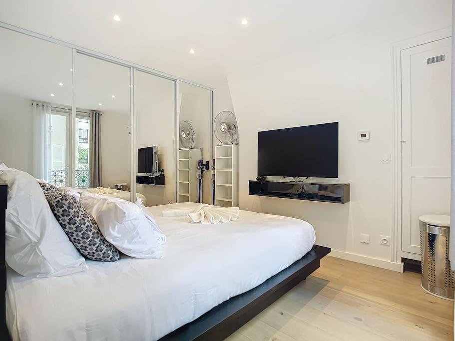 - une chambre blanche avec un grand lit blanc et une télévision à écran plat dans l'établissement Studio 49-Le Cocon-Métro à 1mn, à Paris