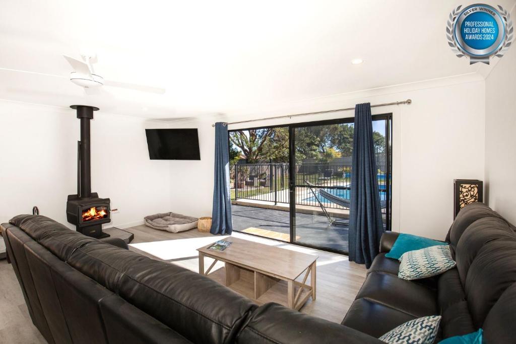 a living room with a leather couch and a fireplace at Pipers Spot - Pet Friendly - Fireplace with Swimming Pool in Culburra Beach