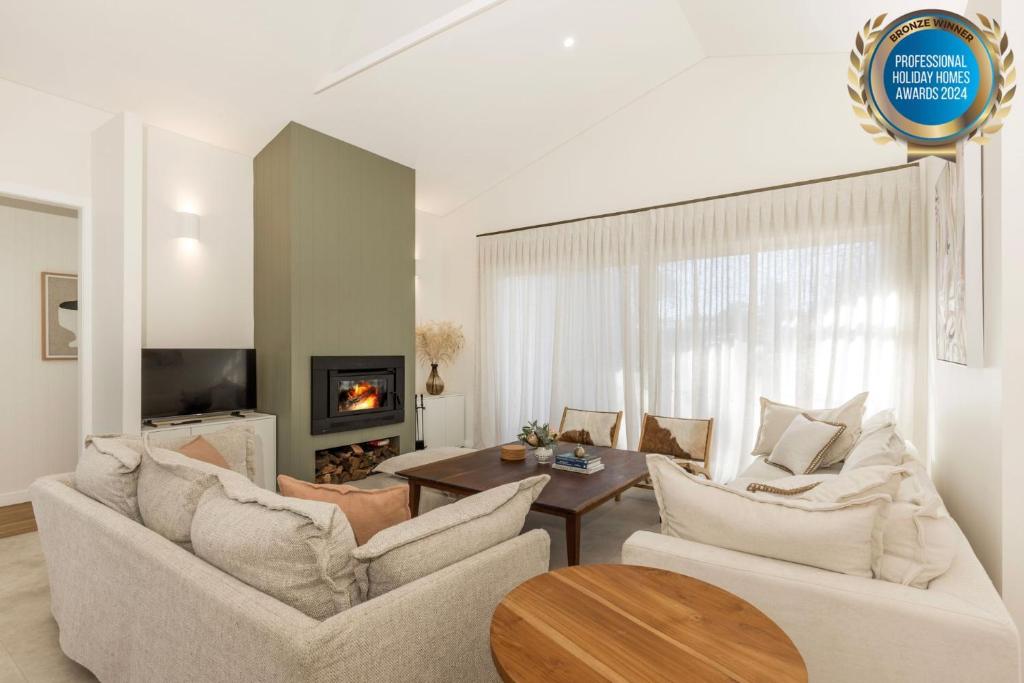 a living room with two white couches and a table at Carramar - Fireplace - Absolute Waterfront in Culburra Beach