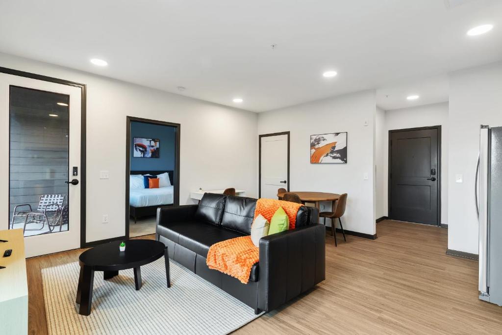 a living room with a black couch and a table at CozySuites on Mass with garage parking #3 in Indianapolis