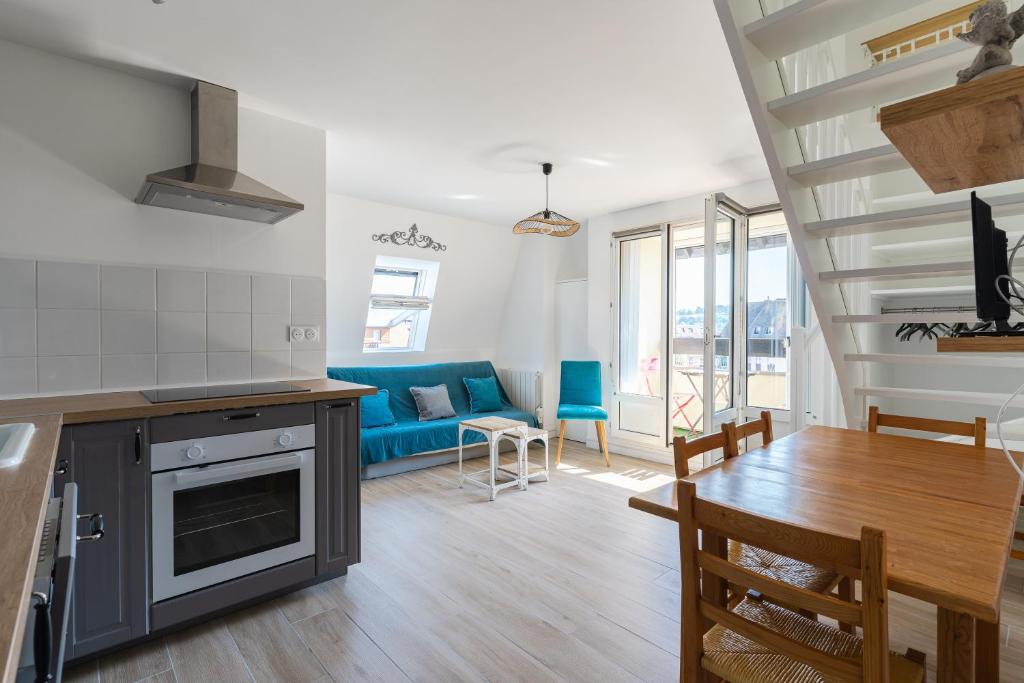 Il comprend une cuisine et un salon doté d'un canapé bleu. dans l'établissement Duplex du bord de mer - Appt à 50m de la plage, à Villers-sur-Mer