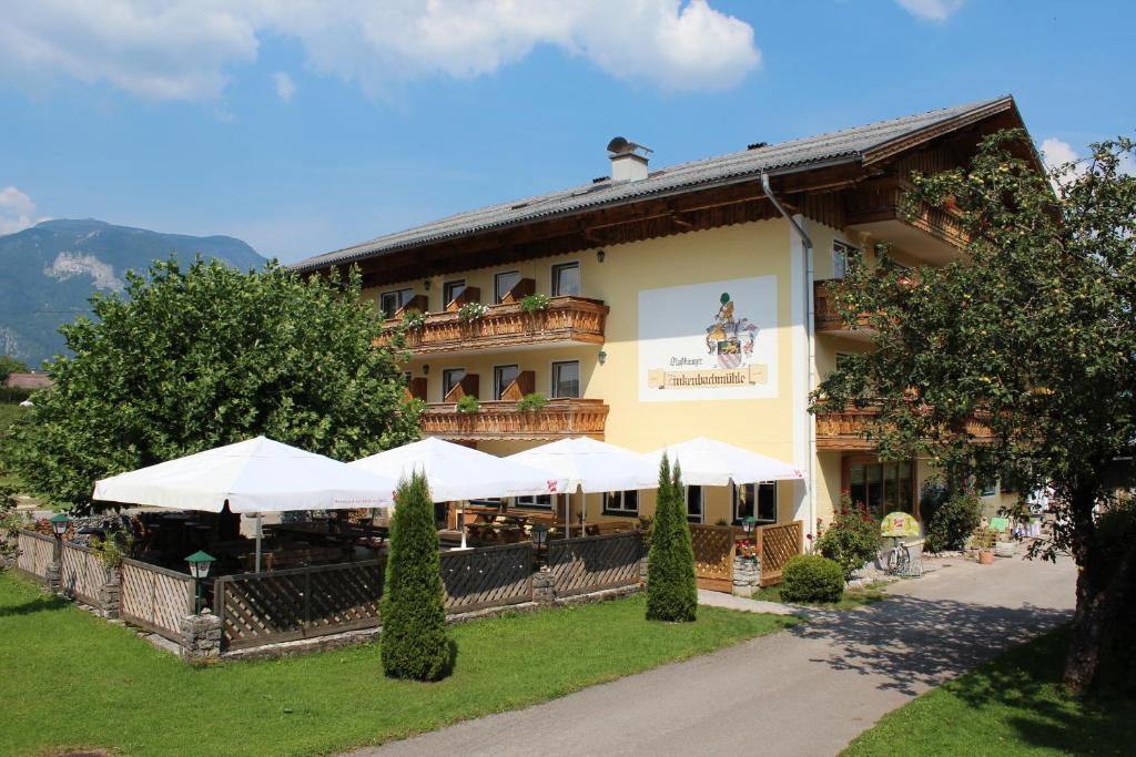 ein Gebäude mit weißen Sonnenschirmen davor in der Unterkunft Gasthof Zinkenbachmühle in Sankt Gilgen
