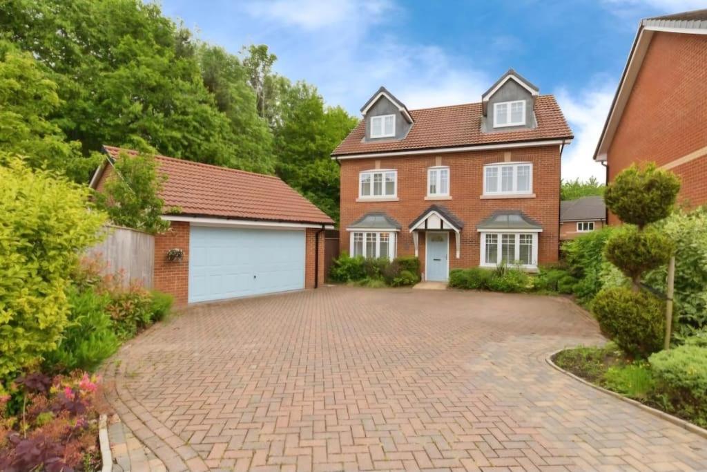 a brick house with a garage and a driveway at Cheshire home by Chelsea in Macclesfield
