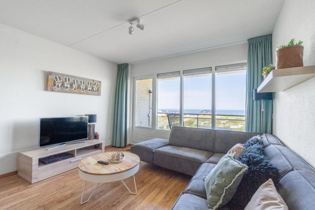 a living room with a couch and a tv at Appartementencomplex Juliana 102 in De Koog