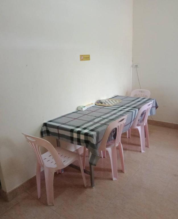 a table with four pink chairs and a table with a checkerboard table at มังกรเลโฮสเทล Mangkonlay Hostel in Ban Khlong Pak