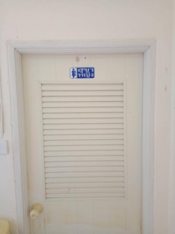 a white garage door with a sign on it at มังกรเลโฮสเทล Mangkonlay Hostel in Ban Khlong Pak