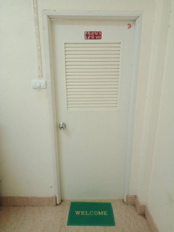 a white door with a welcome sign in front of it at มังกรเลโฮสเทล Mangkonlay Hostel in Ban Khlong Pak
