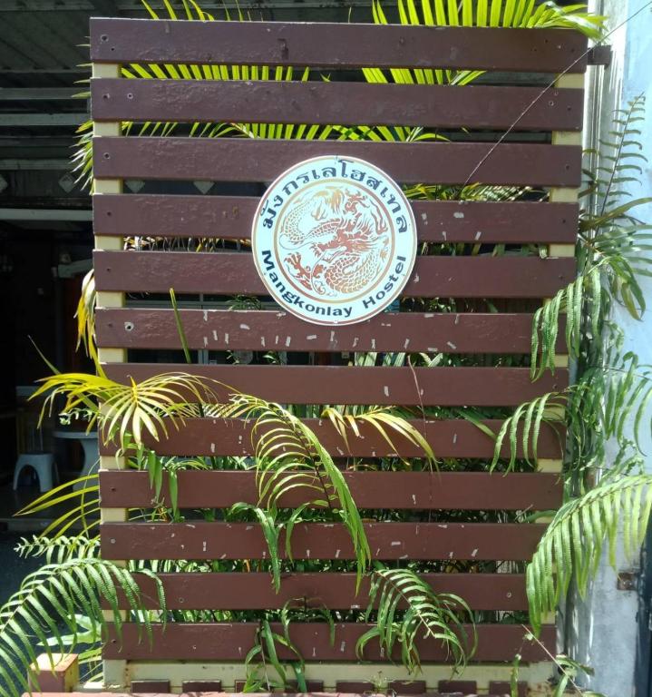 a sign on a wooden fence with a plant at มังกรเลโฮสเทล Mangkonlay Hostel in Ban Khlong Pak