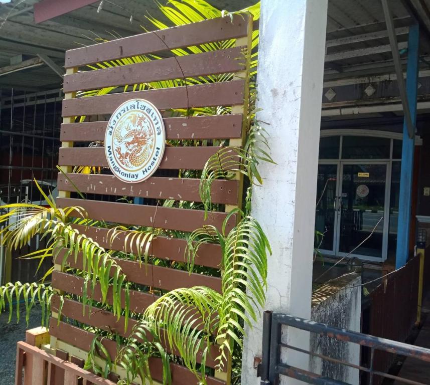 a sign on the side of a building with a plant at มังกรเลโฮสเทล Mangkonlay Hostel in Ban Khlong Pak