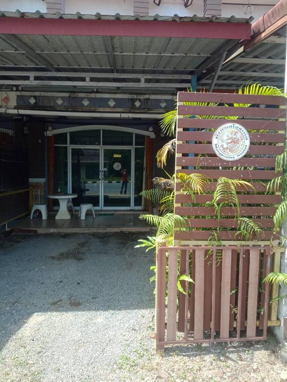 a building with a fence and a sign in front of it at มังกรเลโฮสเทล Mangkonlay Hostel in Ban Khlong Pak