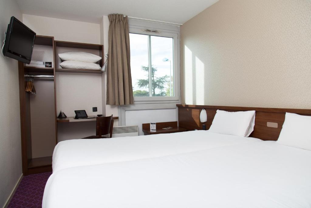 Rúm í herbergi á Brit Hotel Toulouse Colomiers – L’Esplanade