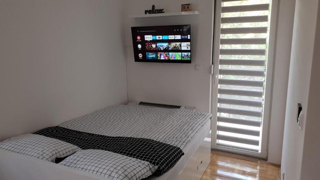 a small bed in a room with a tv on the wall at Apartman Savic 1 in Bijeljina