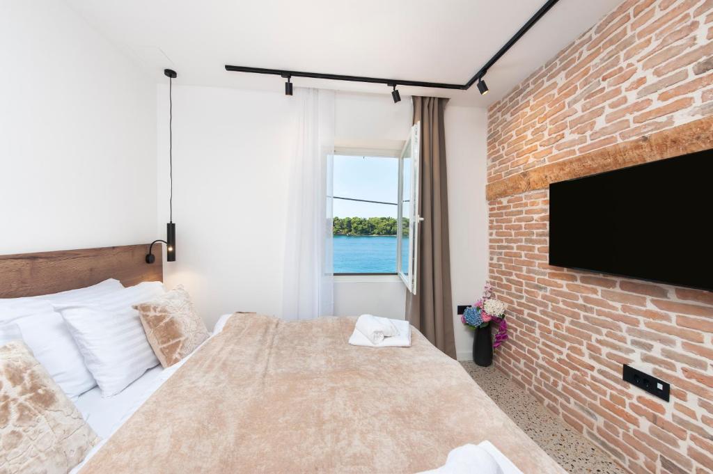 Un dormitorio con una cama y una pared de ladrillo. en La Riva Luxury Rooms, en Rovinj