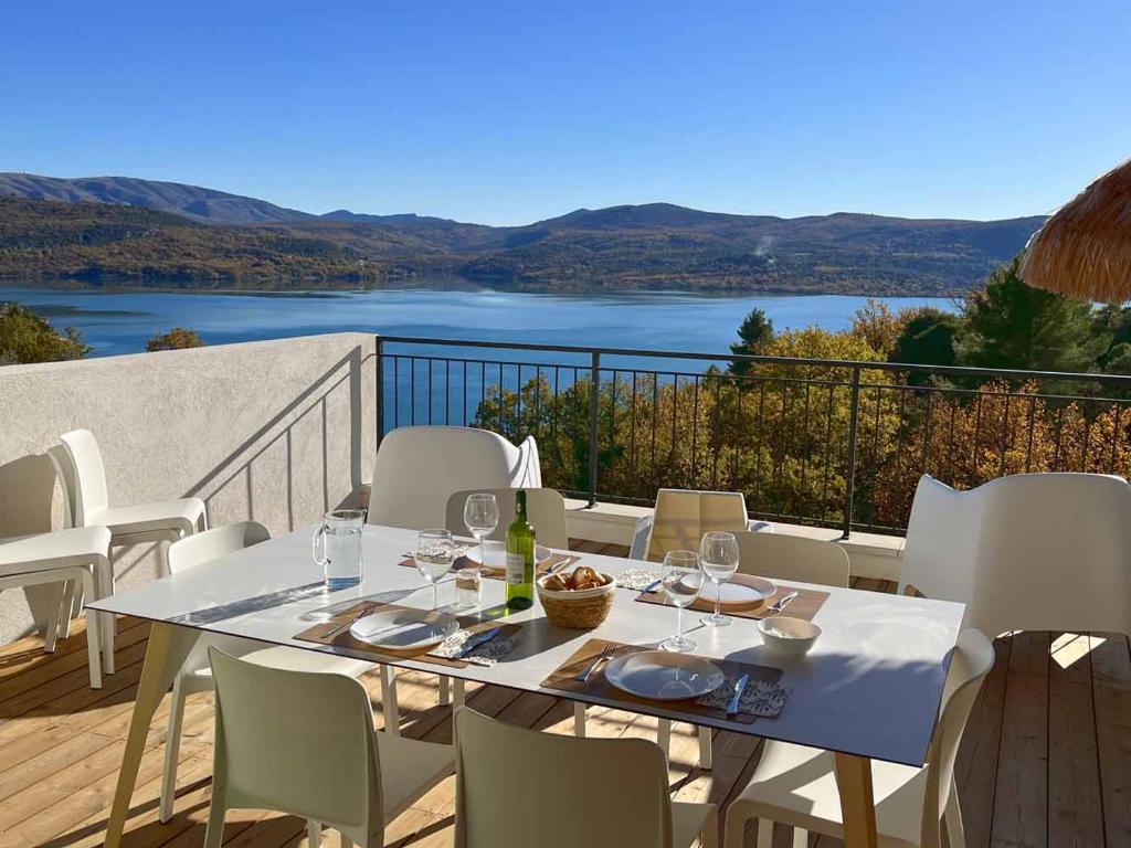 een tafel en stoelen op een balkon met uitzicht op een meer bij Villa Fautea Verdon in Sainte-Croix-de-Verdon