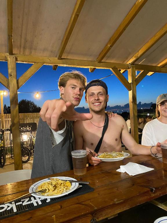 two men standing at a table with plates of food at WOT Ericeira Surf Hostel in Ericeira