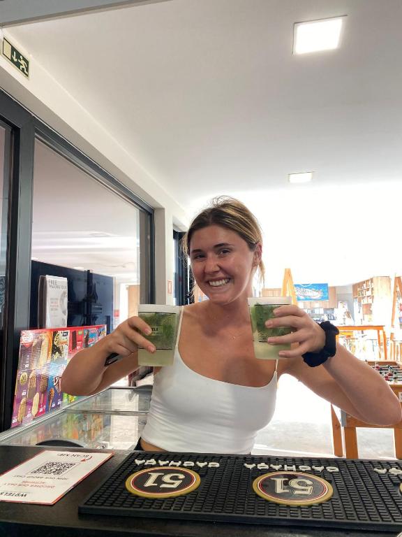a woman is holding up two green drinks at WOT Ericeira Surf Hostel in Ericeira