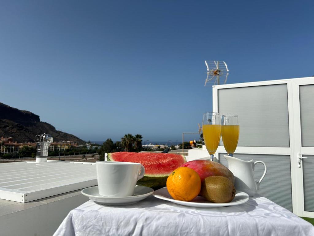 una mesa con un plato de fruta y dos vasos de zumo en NORAY Playa de Mogán, en Puerto de Mogán