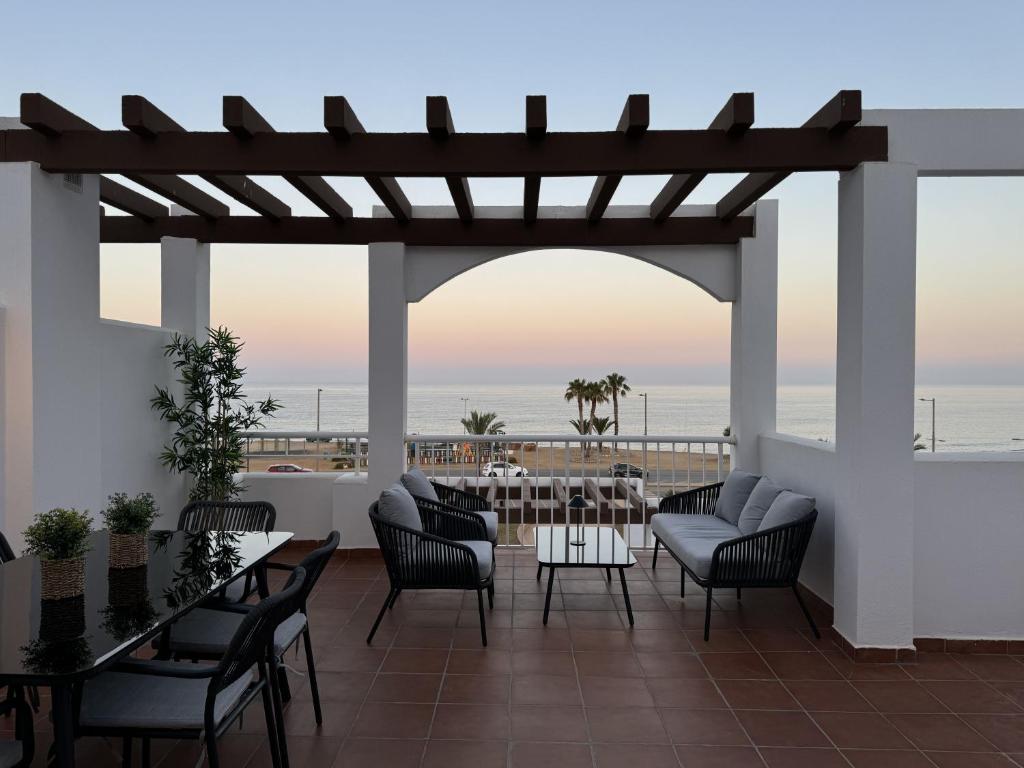 a patio with tables and chairs and a view of the ocean at Apartamento con piscina frente al mar en Mojácar playa para familias y parejas de más de 30 años in Mojácar