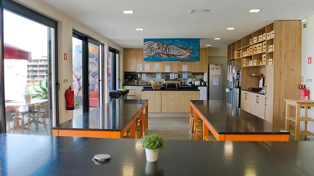 a large kitchen with two tables and a refrigerator at WOT Ericeira Surf Hostel in Ericeira