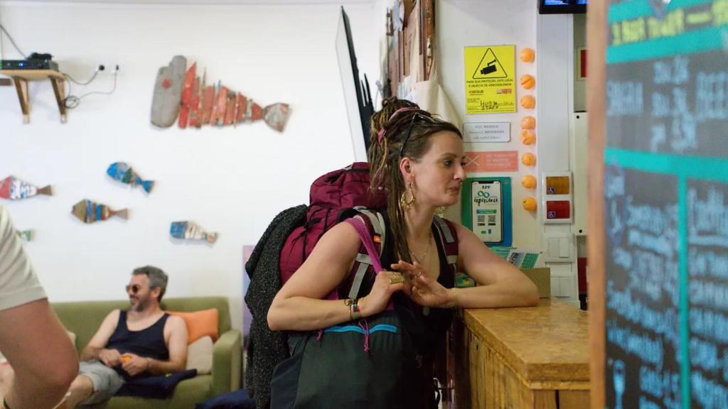 a woman standing at a counter eating food at WOT Ericeira Surf Hostel in Ericeira